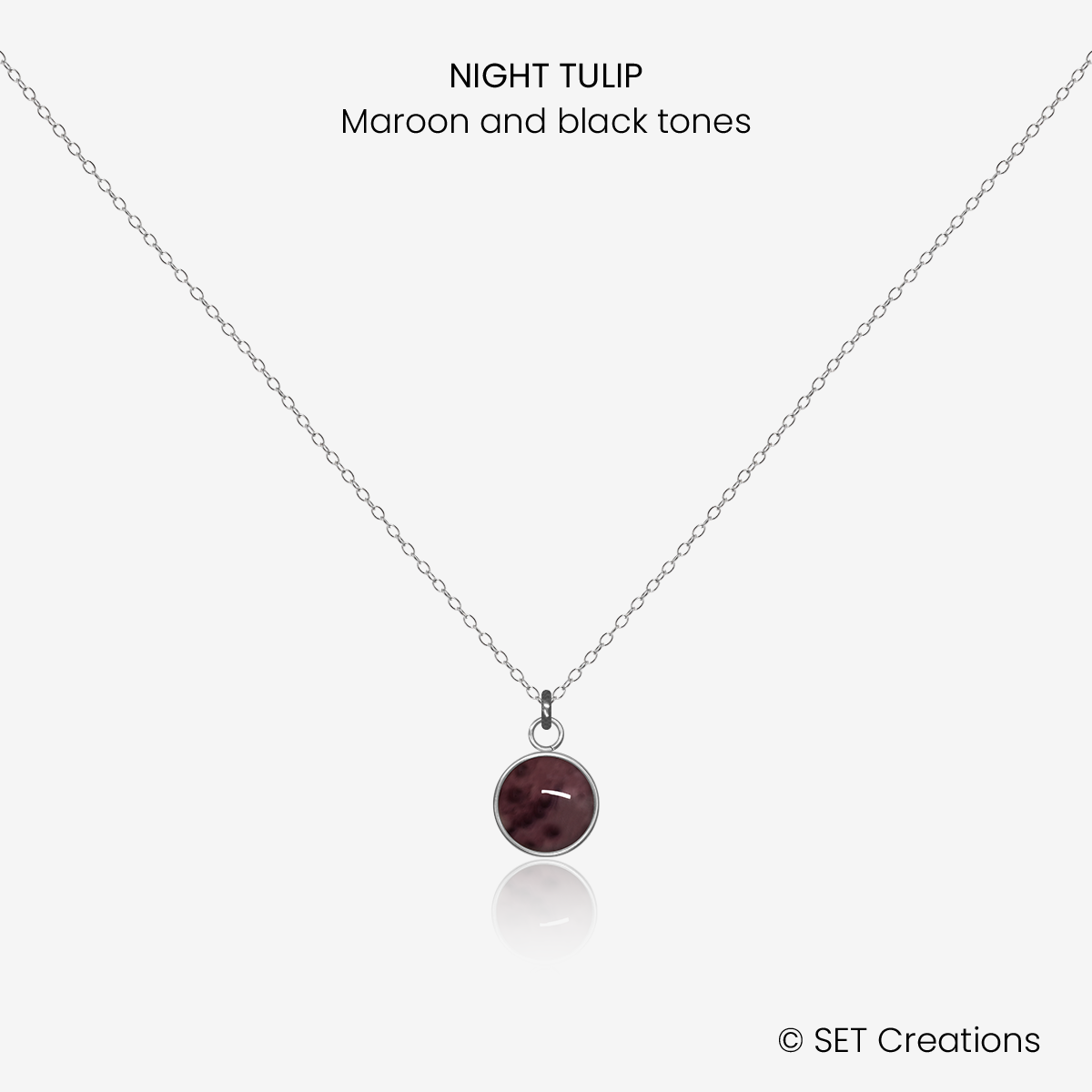 6mm fused glass circular cabochon set into a steel base and attached to a 400mm stainless steel pendant chain via jump ring. Cabochon colour: Night Tulip = maroon and black marble effect.