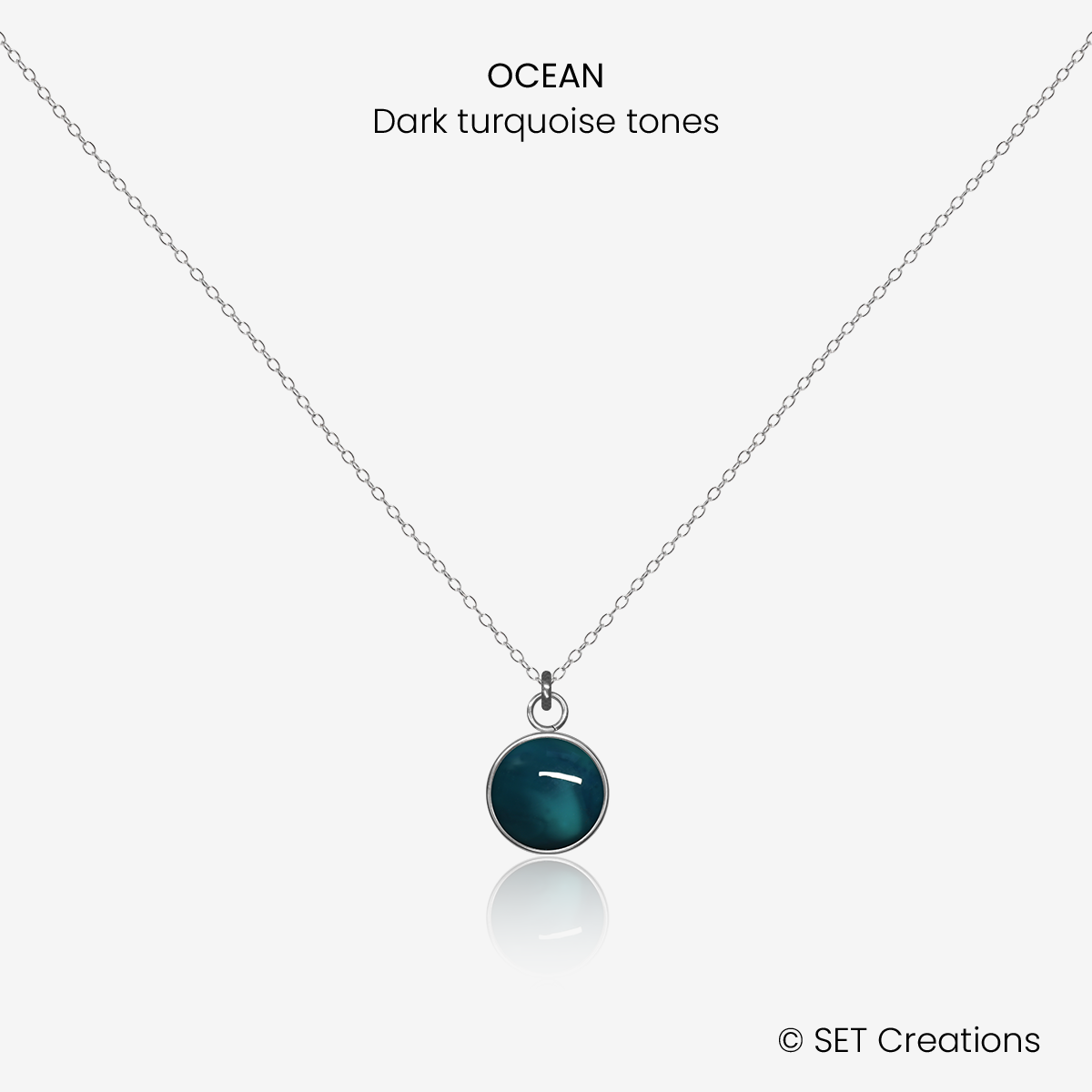 8mm fused glass circular cabochon set into a steel base and attached to a 500mm stainless steel pendant chain via jump ring. Cabochon colour: Ocean = deep turquoise and aqua marble effect.