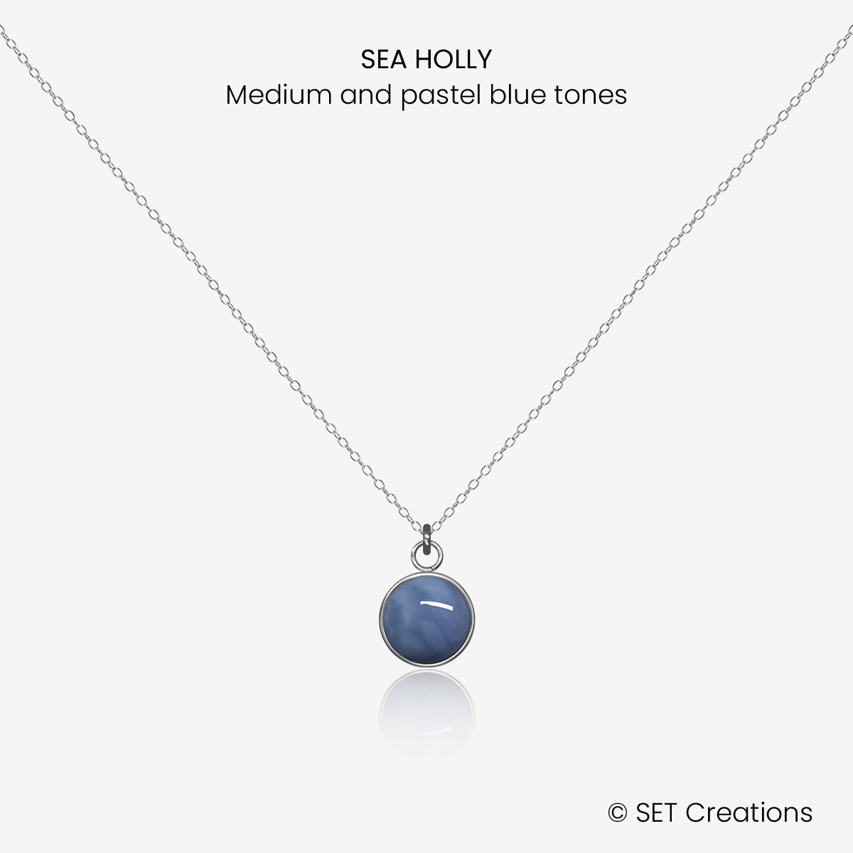 8mm fused glass circular cabochon set into a steel base and attached to a 500mm stainless steel pendant chain via jump ring. Cabochon colour: Sea Holly = medium and pastel blue marble effect.