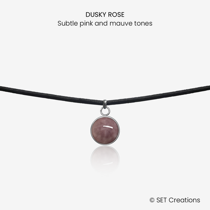 10mm fused glass circular cabochon set into a steel base and attached to a 380mm faux suede black cord via jump ring. Cabochon colour: Dusky Rose = subtle pink and mauve marble effect.