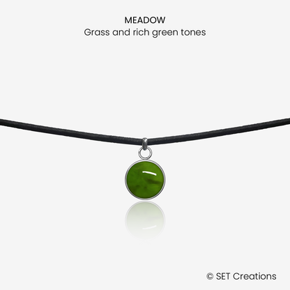 10mm fused glass circular cabochon set into a steel base and attached to a 380mm faux suede black cord via jump ring. Cabochon colour: Meadow = grass and rich green marble effect.