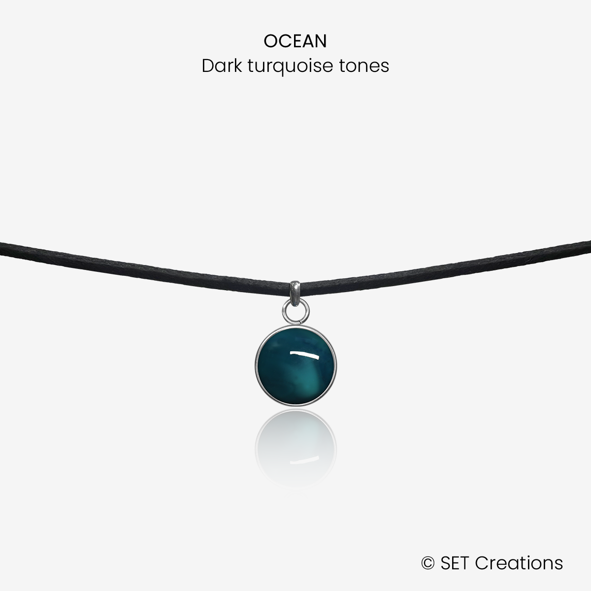 10mm fused glass circular cabochon set into a steel base and attached to a 380mm faux suede black cord via jump ring. Cabochon colour: Ocean = deep turquoise and aqua marble effect.