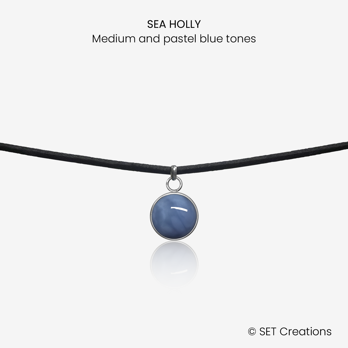10mm fused glass circular cabochon set into a steel base and attached to a 380mm faux suede black cord via jump ring. Cabochon colour: Sea Holly = medium and pastel blue marble effect.