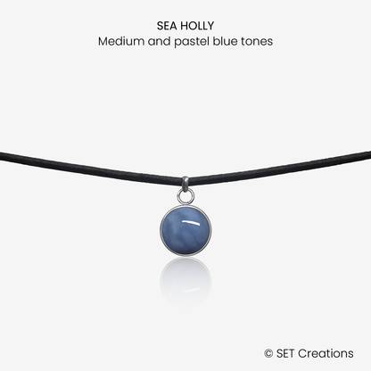 10mm fused glass circular cabochon set into a steel base and attached to a 380mm faux suede black cord via jump ring. Cabochon colour: Sea Holly = medium and pastel blue marble effect.