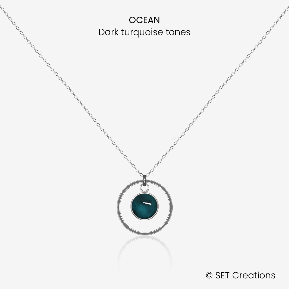 6mm fused glass circular cabochon set into a steel base, framed with a 16mm steel hoop and attached to a 400mm stainless steel pendant chain via jump ring. Cabochon colour: Ocean = deep turquoise and aqua marble effect.