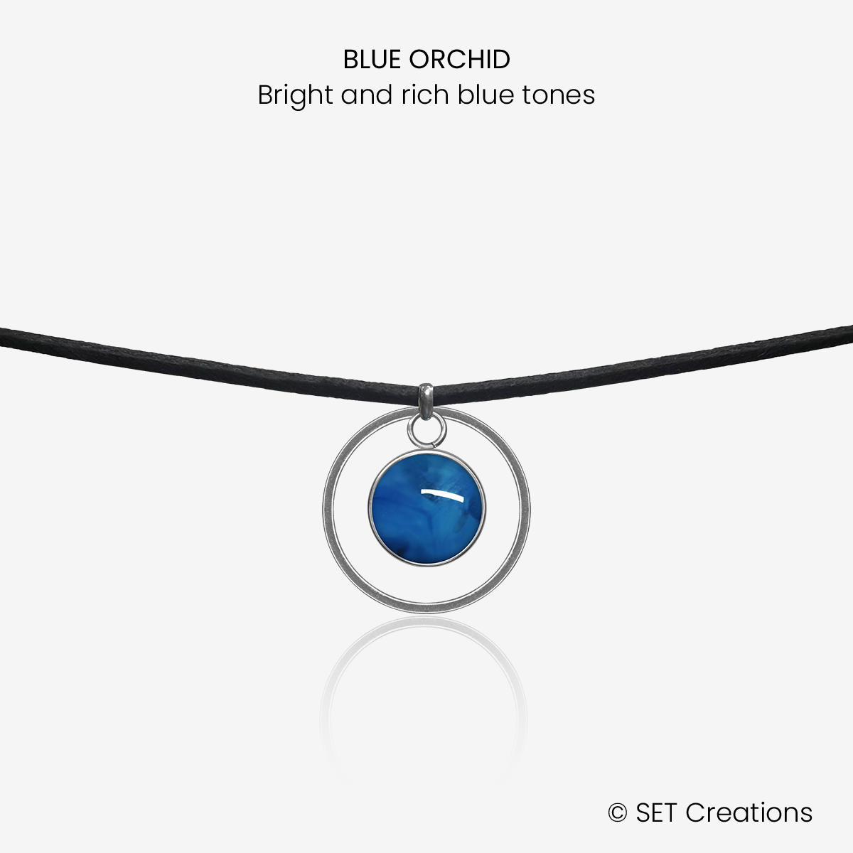 10mm fused glass circular cabochon set into a steel base, framed with a 20mm steel hoop and attached to a 380mm faux suede black cord via jump ring. Cabochon colour: Blue Orchid = bright and rich blue marble effect.