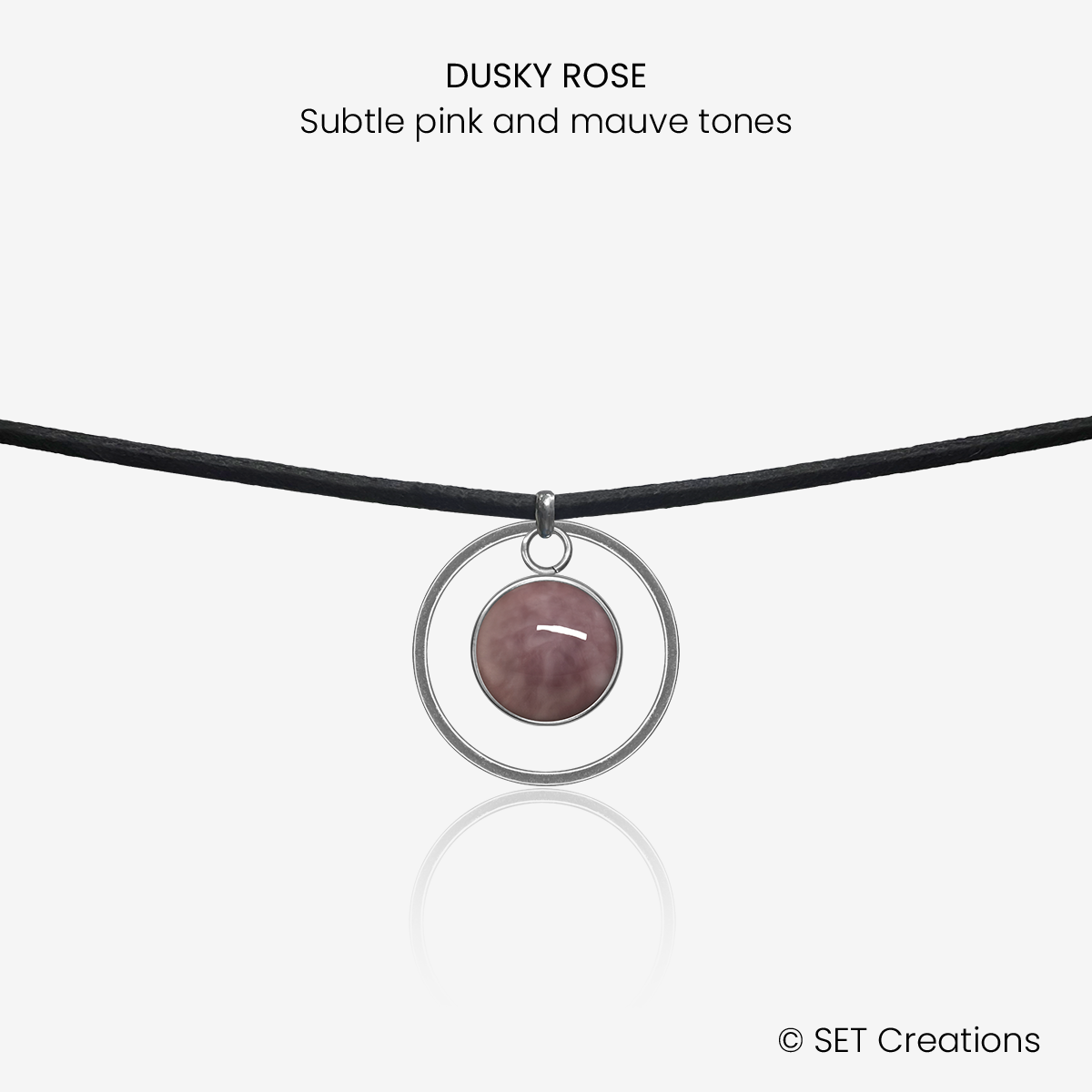 10mm fused glass circular cabochon set into a steel base, framed with a 20mm steel hoop and attached to a 380mm faux suede black cord via jump ring. Cabochon colour: Dusky Rose = subtle pink and mauve marble effect.
