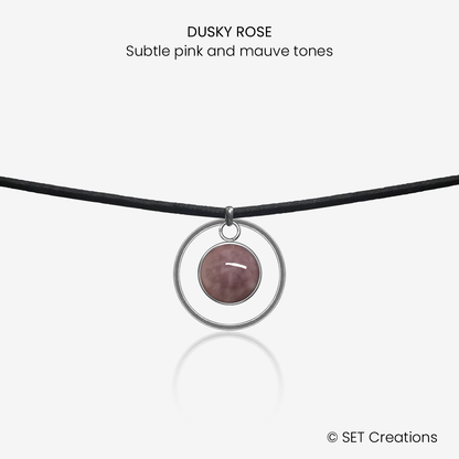 10mm fused glass circular cabochon set into a steel base, framed with a 20mm steel hoop and attached to a 380mm faux suede black cord via jump ring. Cabochon colour: Dusky Rose = subtle pink and mauve marble effect.
