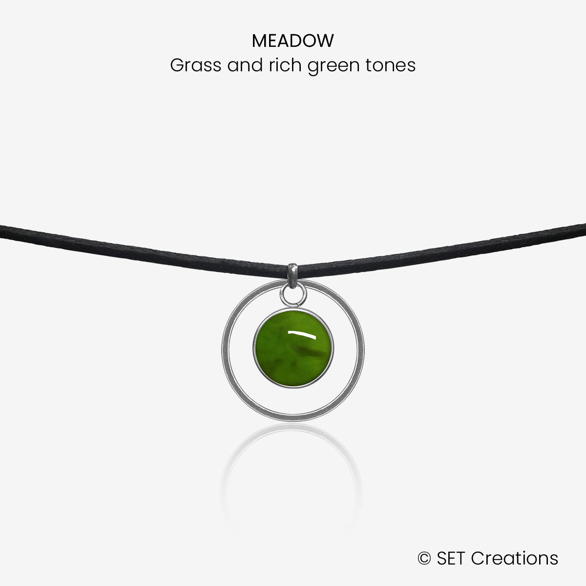 10mm fused glass circular cabochon set into a steel base, framed with a 20mm steel hoop and attached to a 380mm faux suede black cord via jump ring. Cabochon colour: Meadow = grass and rich green marble effect.
