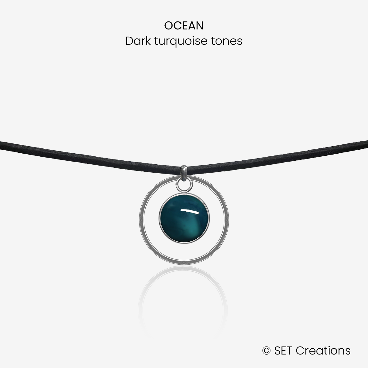 10mm fused glass circular cabochon set into a steel base, framed with a 20mm steel hoop and attached to a 380mm faux suede black cord via jump ring. Cabochon colour: Ocean = deep turquoise and aqua marble effect.