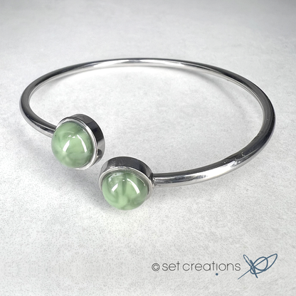 2 x 8mm fused glass circular cabochons set into stainless steel adjustable 2mm thick wire bangles. Cabochon colour: Olive = pale and subtle green marble effect.